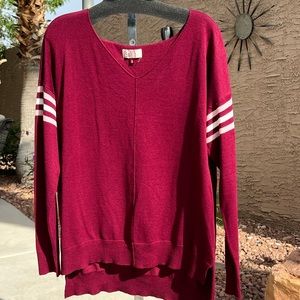 Burgundy sweater with striped sleeves.